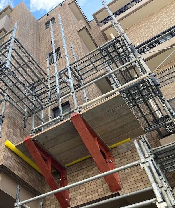 張り出し足場は、建物の外側に張り出し材を取り付け、その上に、踏板を設置したり、くさび緊結式足場や枠組足場などの通常の足場を組み立てたりする構造の足場です。
建物の外壁から張り出した「ベランダのような足場」をイメージすると分かりやすいでしょう。